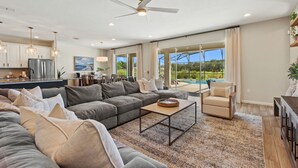 A spacious living room with a large sectional sofa, a coffee table, and a view of a swimming pool.