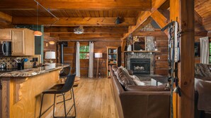 A log cabin interior with a kitchen, dining area, and living room. - Private Log Cabin Near Blowing Rock | Hot Tub, Fire Pit & Creekside Trails (Blowing Rock)