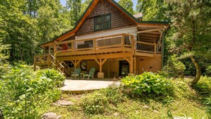 A cabin with a wooden exterior, a balcony, and a covered patio area. - Private Log Cabin Near Blowing Rock | Hot Tub, Fire Pit & Creekside Trails (Blowing Rock)