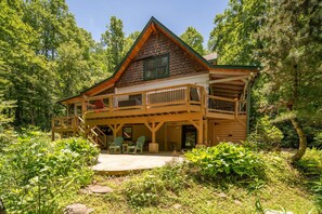 A cabin with a wooden exterior, a balcony, and a covered patio area. - Private Log Cabin Near Blowing Rock | Hot Tub, Fire Pit & Creekside Trails (Blowing Rock)