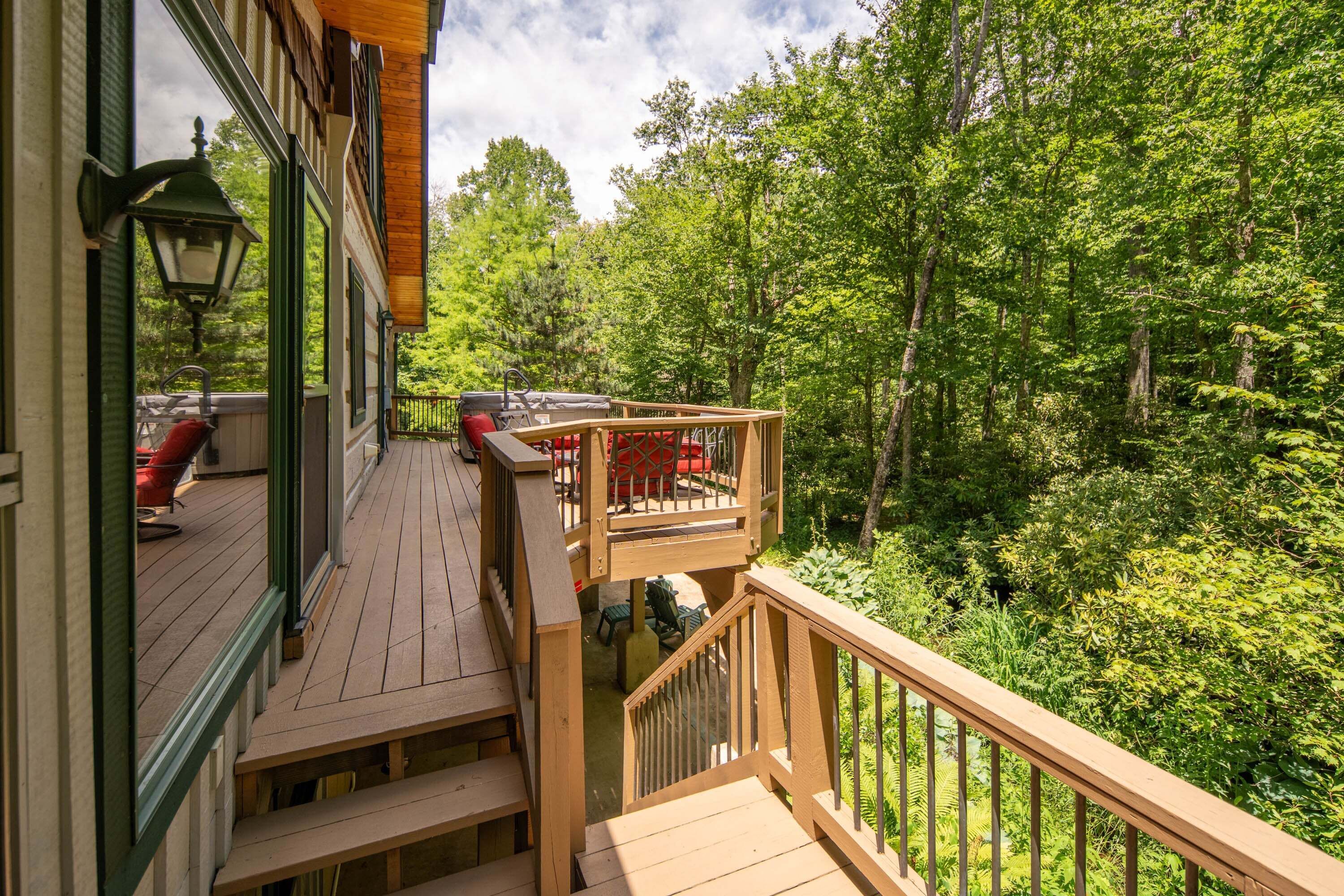 Une terrasse en bois avec des meubles d’extérieur, un barbecue et une vue sur une zone boisée.