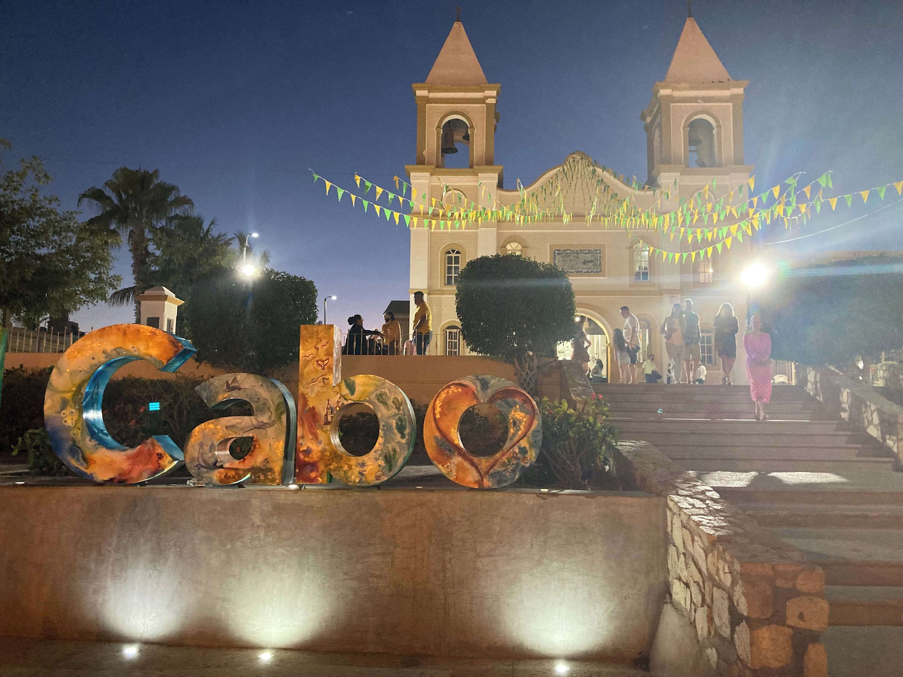 A building with two towers and a large sign with the word 'Cabo' in the foreground.