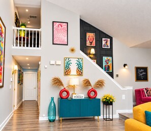 A modern interior with a staircase, artwork, and a teal console.