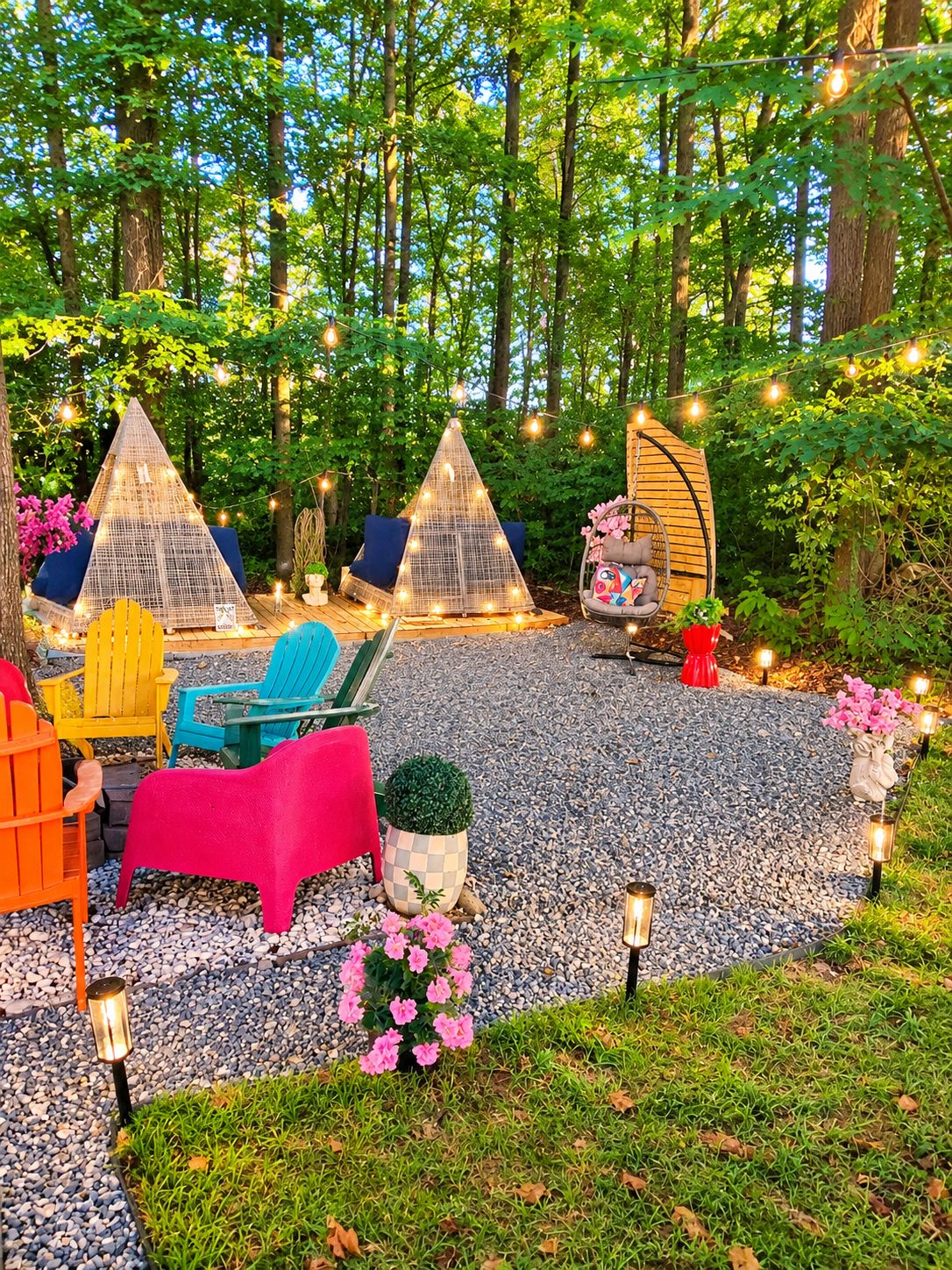 A campsite with two conical tents, outdoor seating, and string lights.