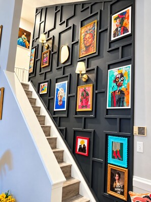 A staircase with a black wall adorned with various framed artworks.