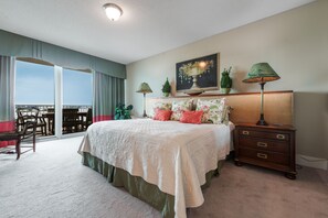 A bedroom with a large bed, a nightstand, a dresser, a chair, a balcony with a view, and a painting on the wall. - Cozy Three Bedroom Condo. Complimentary Boat Slip! (Orange Beach)