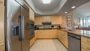 Una cucina moderna con elettrodomestici in acciaio inossidabile, pensili in legno e pavimento piastrellato.