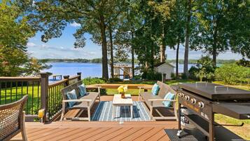 Une terrasse dotée de mobilier d’extérieur, d’un barbecue et offrant une vue sur un lac.