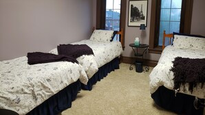 Un dormitorio con dos camas individuales, una mesita con una lámpara y un cuadro en la pared.