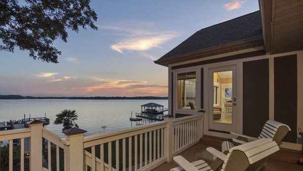 A deck with a view of a lake, a covered dock, and a building with a door and windows. - Sunset Pointe - Entertainers Dream with Amazing Lake Norman Views (Terrell)