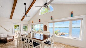 A spacious dining area with a large table and chairs, large windows with a view of the water, and a ceiling fan. - Sunset Pointe - Entertainers Dream with Amazing Lake Norman Views (Terrell)