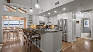 A spacious kitchen with a large island, white cabinetry, stainless steel appliances, and a view to the outside. - Sunset Pointe - Entertainers Dream with Amazing Lake Norman Views (Terrell)