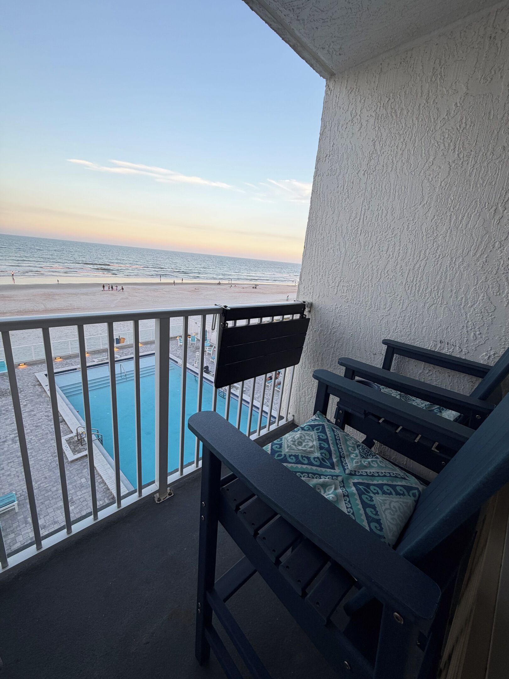 A balcony with a view of a beach and a pool.