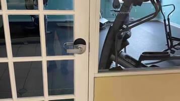 Una porta con un pannello di vetro, un cartello con la scritta 'Grazie per non fumare' e una cyclette all'interno.
