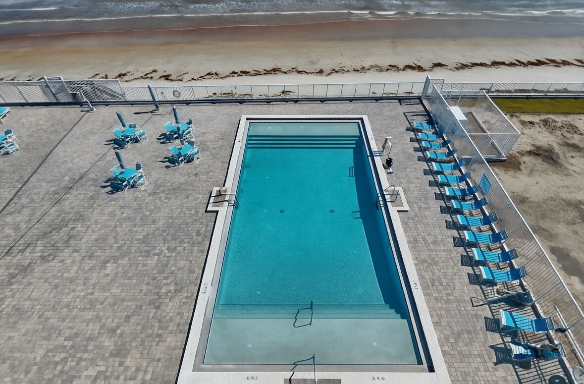 A rectangular pool with a clear blue water surface, surrounded by a tiled deck.