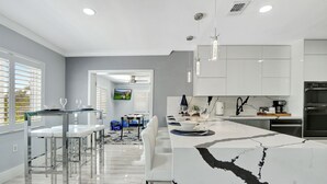 A modern kitchen with white cabinets, a marble countertop, and stainless steel appliances. - The Gardens- Private Pool (Miami Gardens)