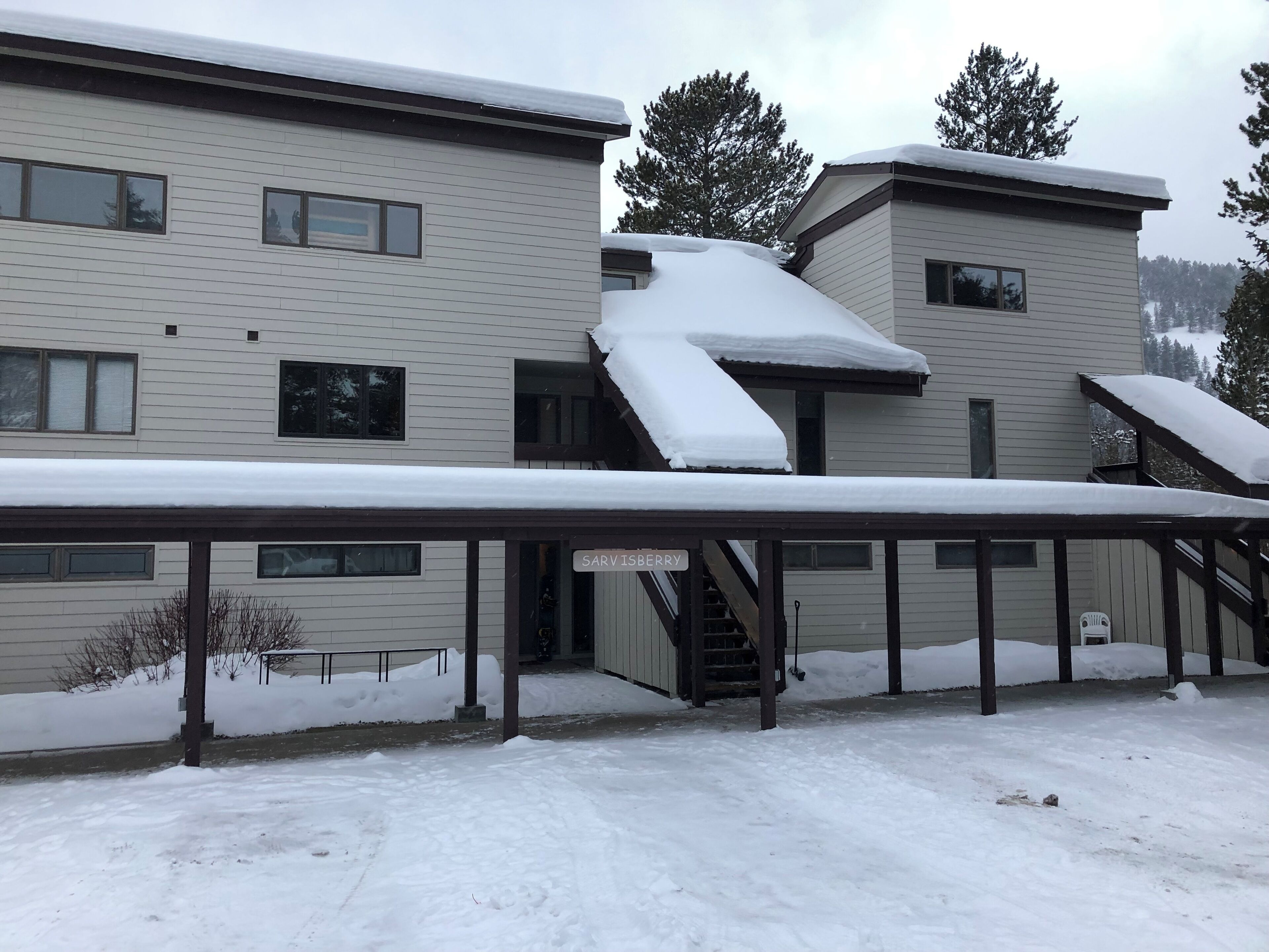 A multi-story building with a covered outdoor area, snow accumulation, and a sign reading "SAVISBERRY".