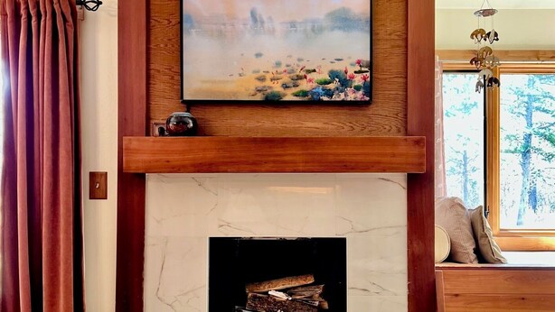 A fireplace with a marble surround, a painting above it, and a window to the right.