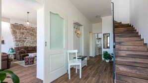 Un interno moderno con una scala in legno, un muro in pietra e una zona living con divano e poltrona.