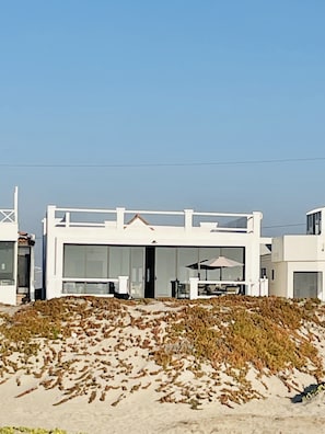 Un bâtiment moderne, de couleur blanche, doté de grandes fenêtres en verre et d’un toit plat.