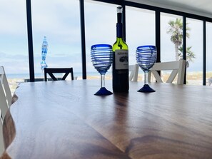 Uma mesa com uma garrafa de vinho Merlot e dois copos de vinho azuis.