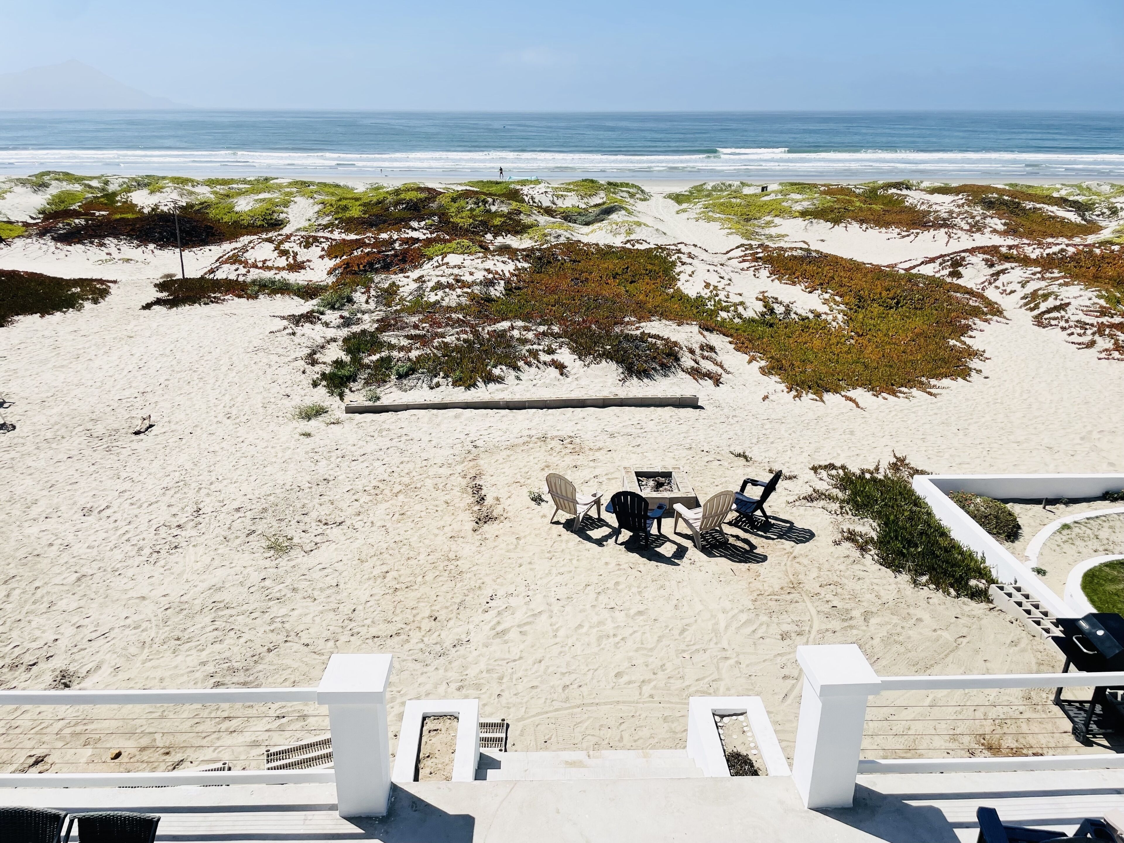 Une plage dotée d’un espace aménagé avec des chaises et un foyer.