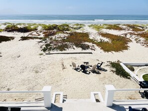 Uma praia com área de estar, cadeiras e lareira.