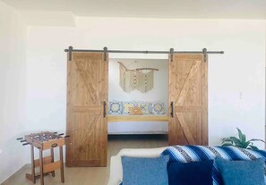 Une chambre avec un lit, une table de baby-foot et une porte coulissante donnant sur un balcon.