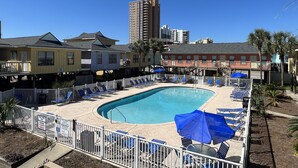 A pool area with sun loungers and umbrellas, surrounded by buildings with balconies. - LOCATION! LOCATION! LOCATION! WEST BEACH Public Access across from complex (Gulf Shores)