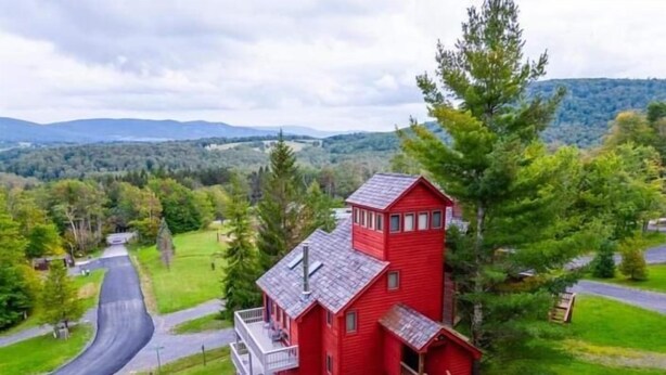 Eine rote Holzhütte mit einer kleinen Veranda und einer Treppe, die zum Haupteingang führt.
