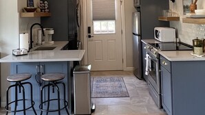 A compact kitchen with a central island, bar stools, a refrigerator, microwave, and a stove. - Come Relax at THE CROW'S NEST , Patriot Pointe at Lake Eufaula.  (Eufaula)