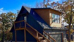 A modern two-story house with a prominent wooden staircase, a garage, and a well-maintained lawn. - Come Relax at THE CROW'S NEST , Patriot Pointe at Lake Eufaula.  (Eufaula)