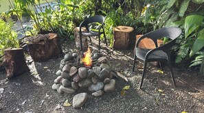 An outdoor seating area with a fire pit surrounded by rocks and chairs.