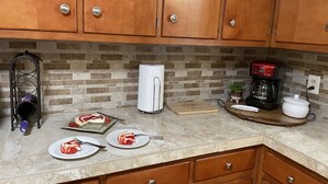 Eine Küche mit Holzschränken, einer Marmorarbeitsplatte, einer Kaffeemaschine, einem Toaster und einem Schneidebrett mit Lebensmitteln.
