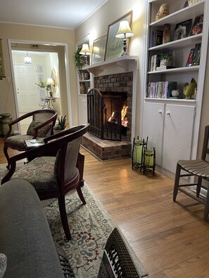 A cozy living room with a fireplace, wooden furniture, and a bookshelf. - Beautiful Home in Safe, Private Setting Only Blocks From the Square (Covington)