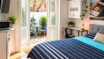 Une chambre dotée d’un grand lit, d’un bureau, d’une chaise, d’une télévision et offrant une vue sur l’extérieur grâce à une porte coulissante.