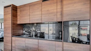 A modern kitchen with wooden cabinetry and a black marble countertop. - Remarkable Wiedikon 2BR w/ Storage & W/D, nr Market, by Blueground (Zurich)