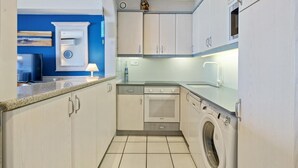 Une cuisine compacte équipée d’un lave-linge, d’un four encastré et d’un four à micro-ondes.