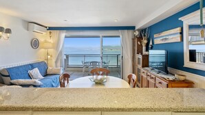 Un salon moderne avec un canapé bleu, une table à manger et un coin cuisine doté de plans de travail en granit.