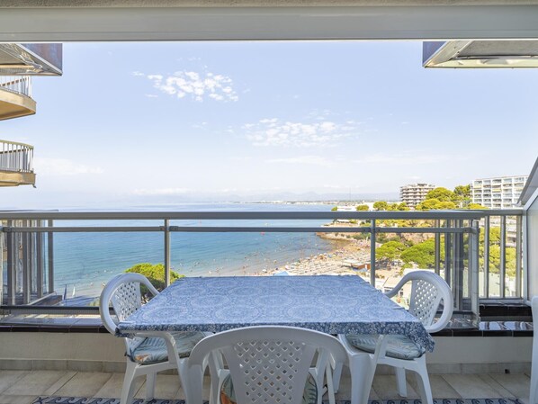 En balkon med et bord og stole med udsigt over en strand.