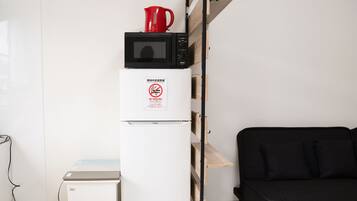 A compact kitchenette with a microwave, a refrigerator, and a coffee maker on the counter.