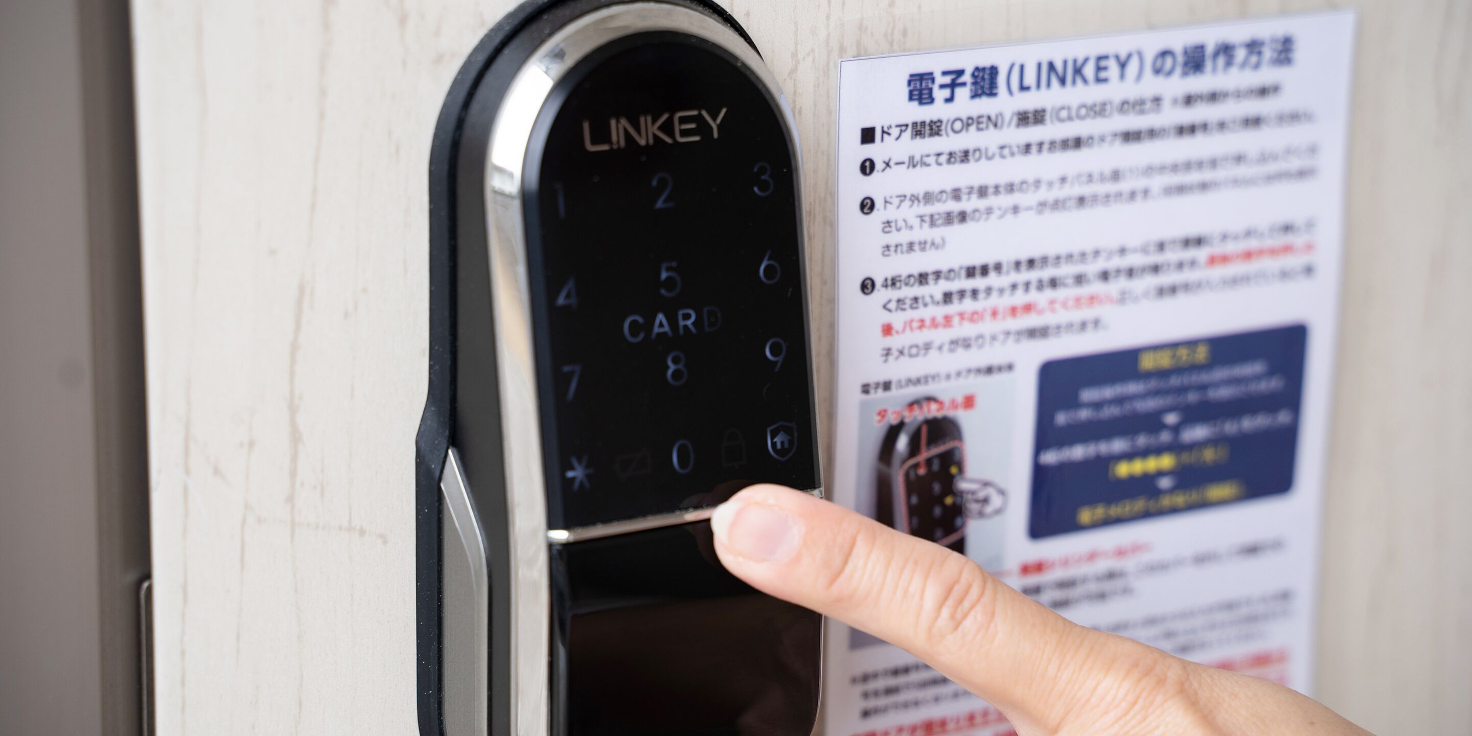 A close-up of a LINKEY electronic keypad on a door, with a hand pressing a button.