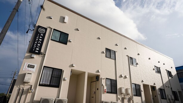 A building with multiple windows, air conditioning units, and a sign indicating it is a hotel. - KARCHIBE ISHIGAKI (Ishigaki)