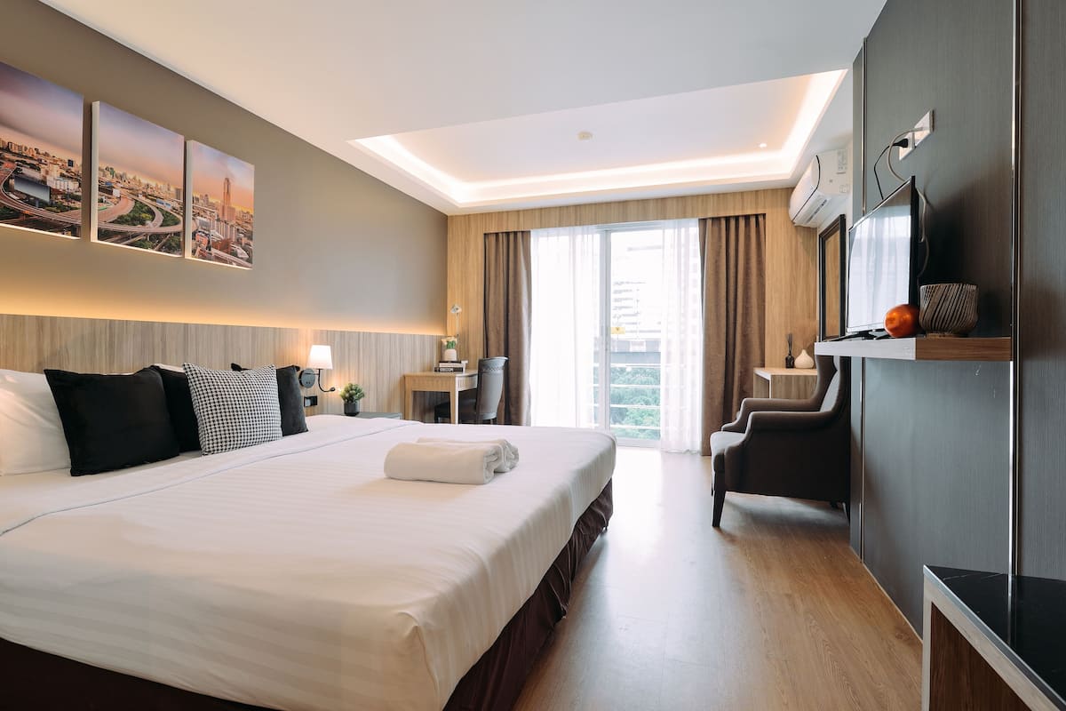 A hotel room with a large bed, a desk, a chair, and a TV.