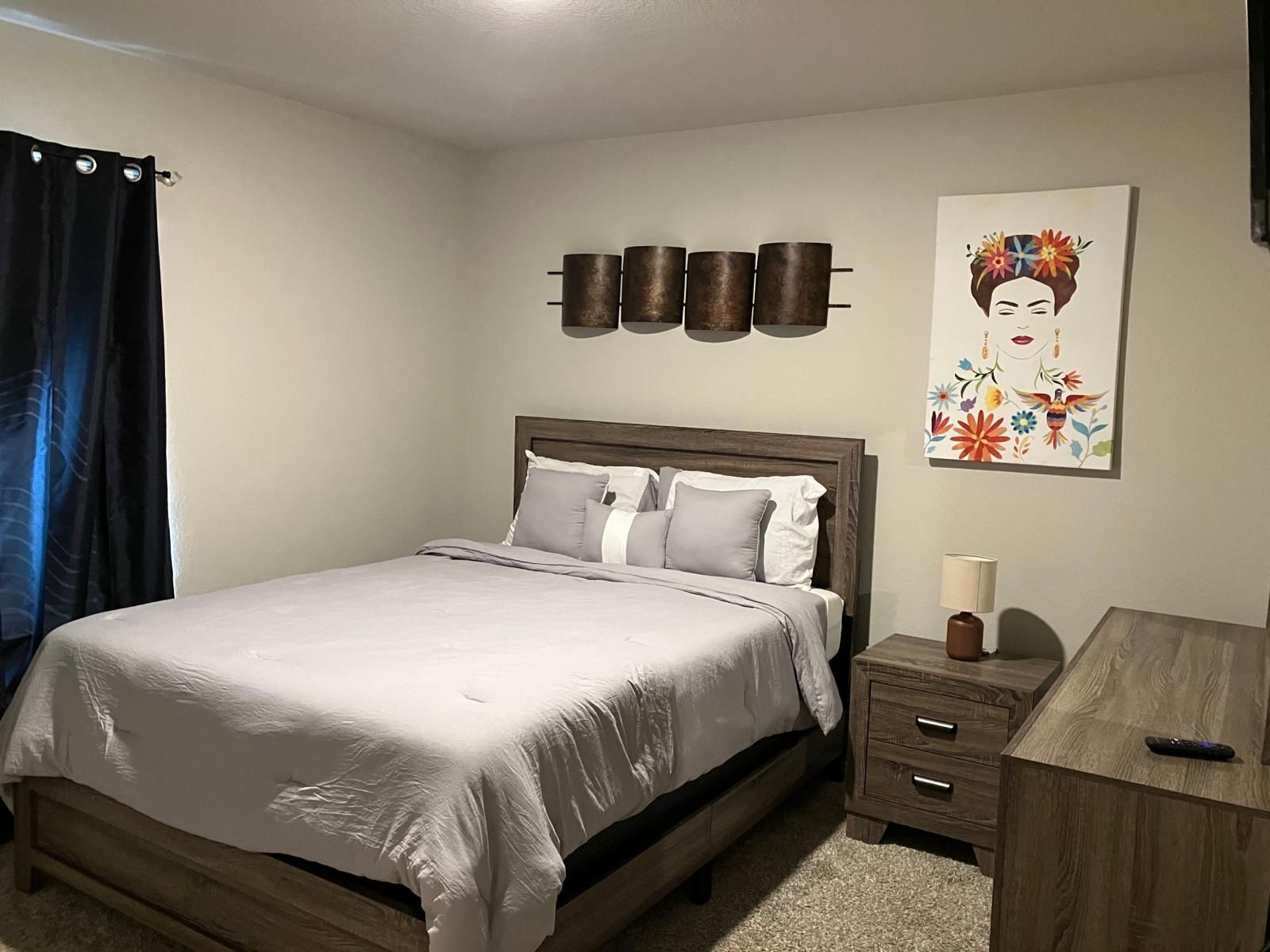 A bedroom with a bed, bedside table, and a wall-mounted artwork.