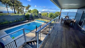 Una terrazza con piscina, mobili da esterno e vista sull'oceano.