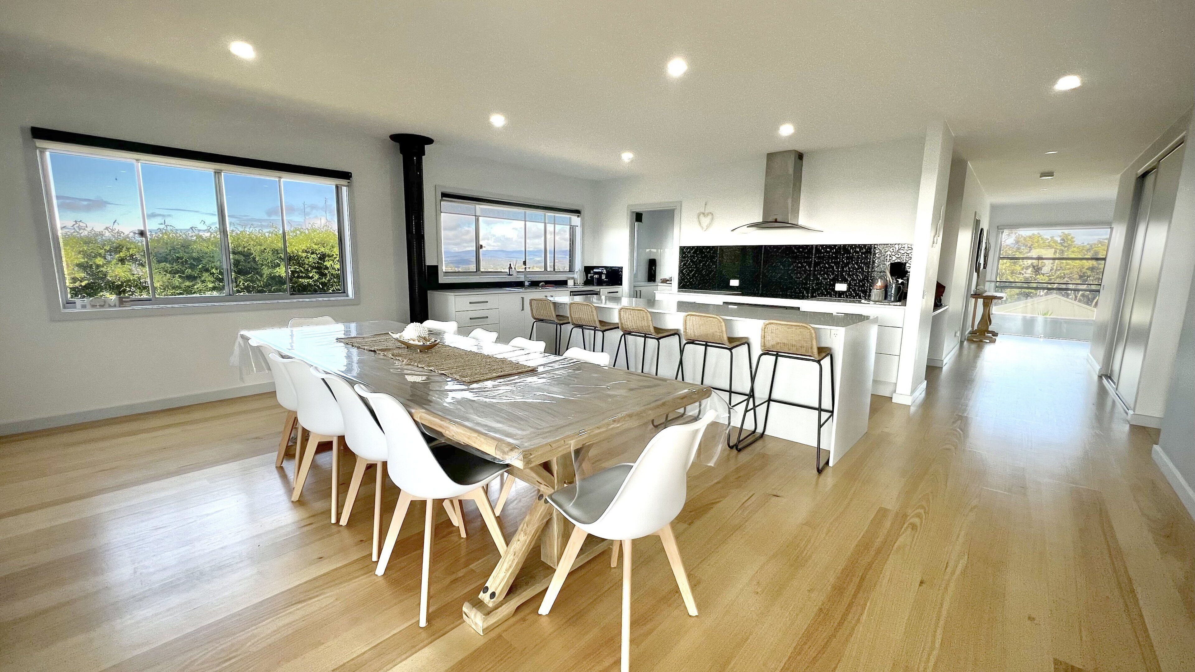 A modern kitchen with a central island, white cabinetry, and a large window offering a view of greenery.
