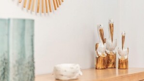 Une console en bois agrémentée d’un miroir décoratif, d’un bol blanc et de trois vases en forme d’oiseau.