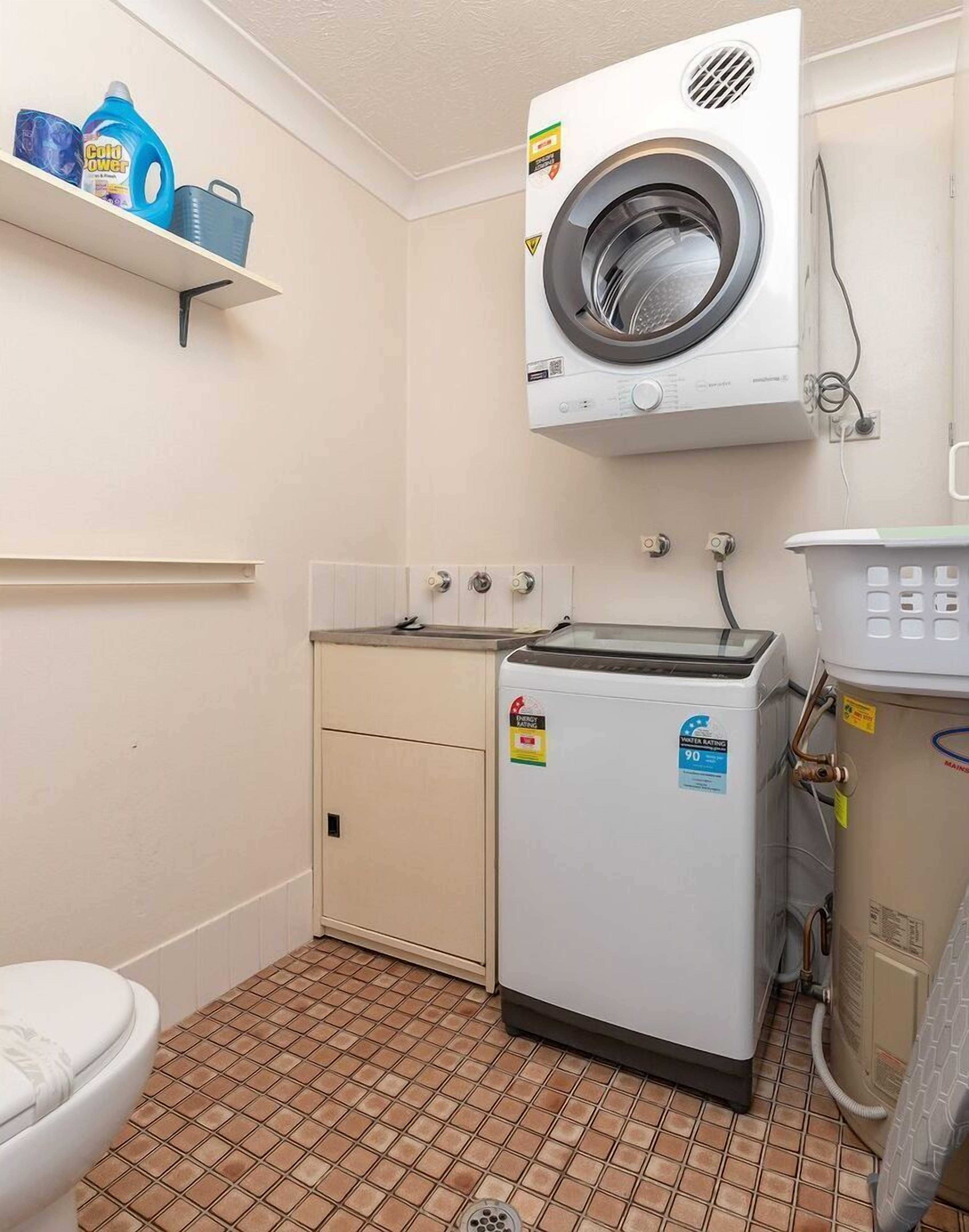 A laundry room with a washing machine, dryer, and a shelf with cleaning supplies.