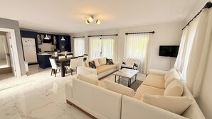 Een moderne woonkamer met een zithoek, een salontafel en een eethoek met stoelen.